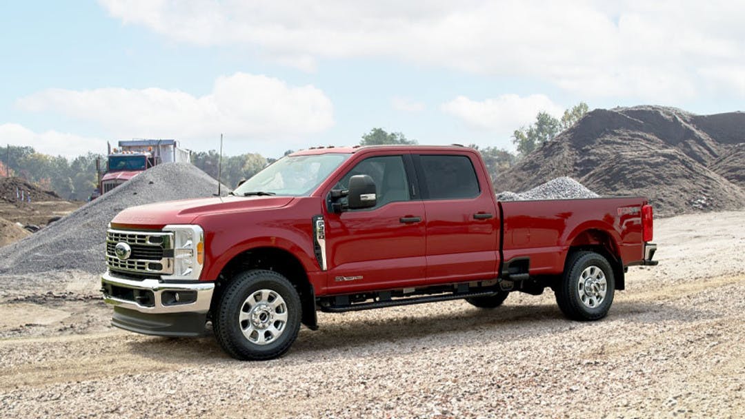 Red 2022-2023 Ford F-350 Super Duty pickup with Air Lift air suspension kit installed. The truck is sitting on a construction site on gravel and is equipped for heavy loads or towing.
