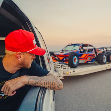 A man in a truck looking back at trailer.